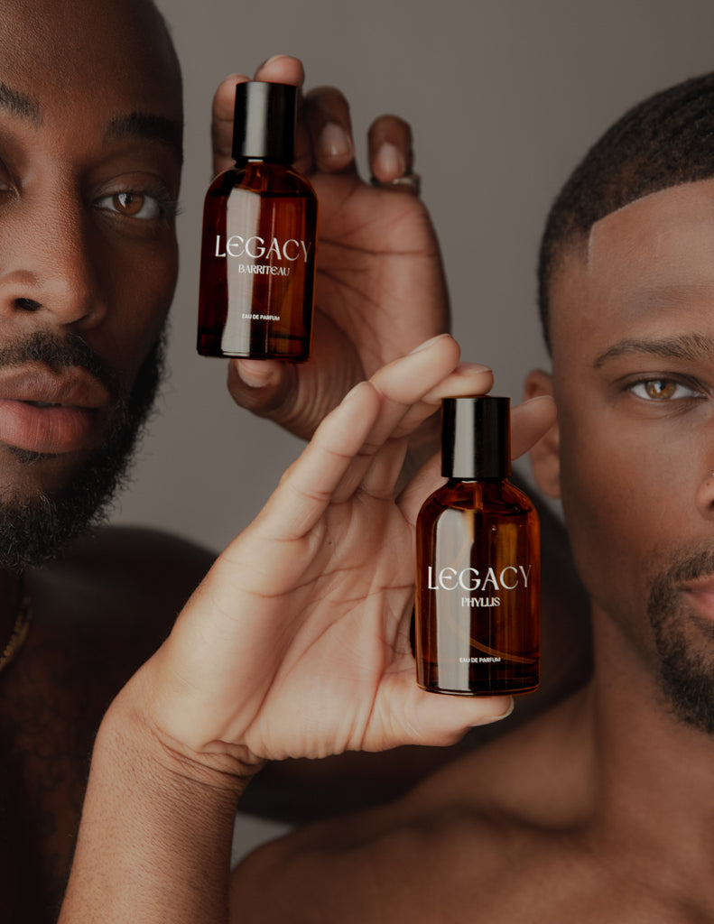 Two men holding bottles of Legacy next to their face